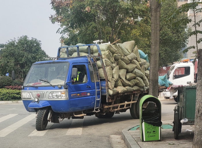 小货车拉十几辆三轮车在路上行驶，一种别样的城市景象